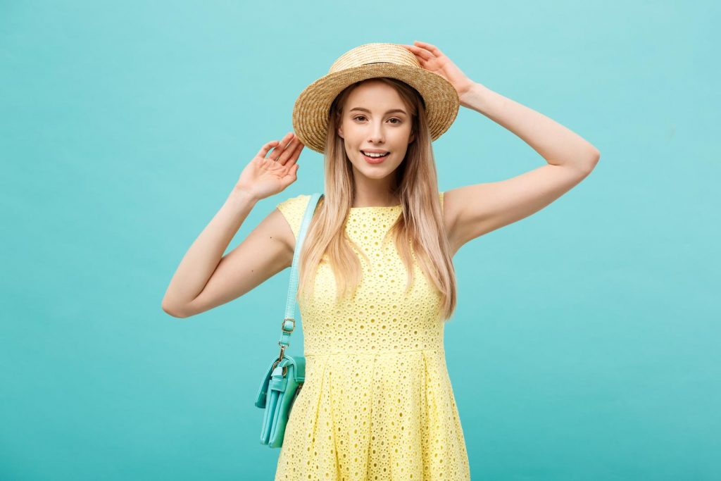 Travel concept - Close up Portrait young beautiful attractive girl wtih trendy hat and smiling. Blue Background. Copy space